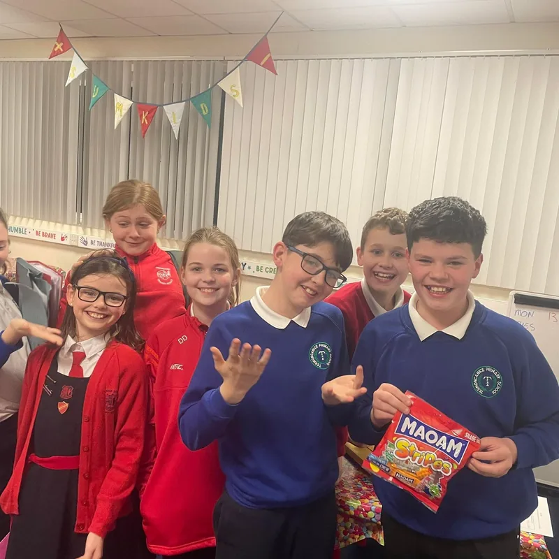A group of smiling transfer club pupils under the Sumkids bunting