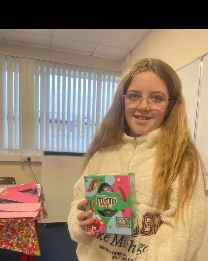 A pupil holding the prize she won in class